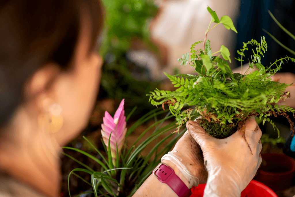 Zdjęcie przedstawia uczestnika warsztatów w czasie, gdy samodzielnie wykonuje kokedamę.